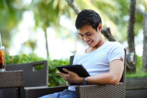 Happy young man enjoying leisure time outdoors using a tablet.